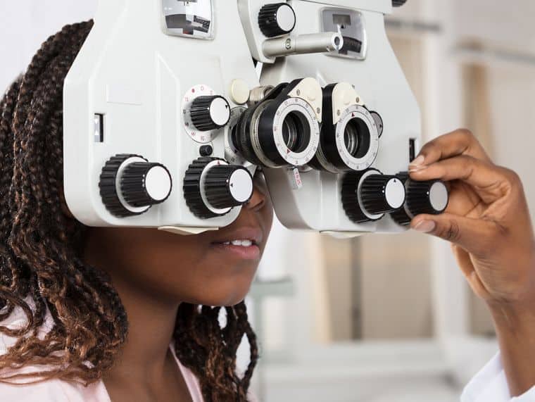 eye doctor giving eye exam to a girl